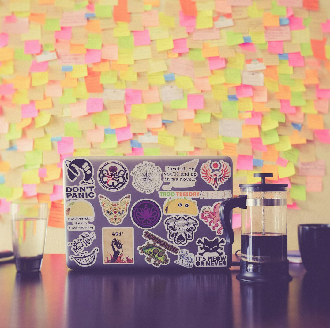 Laptop surrounded by colorful sticky notes on a desk